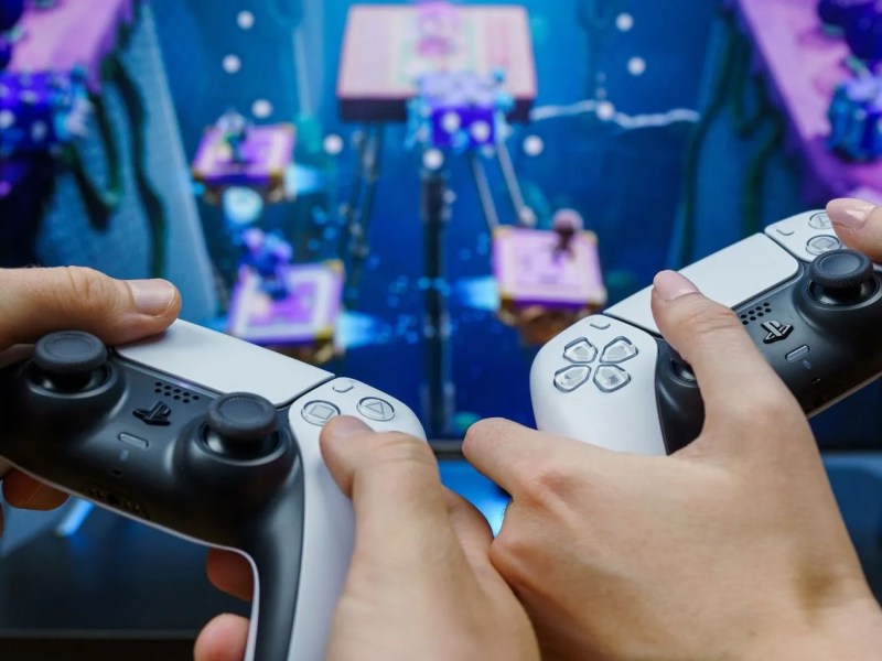 Zwei Personen spielen PS5 mit DualSense-Controllern.